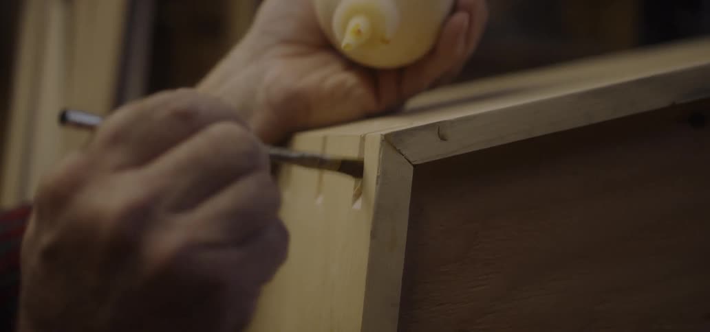 A man is painting glue in the notches of the wood