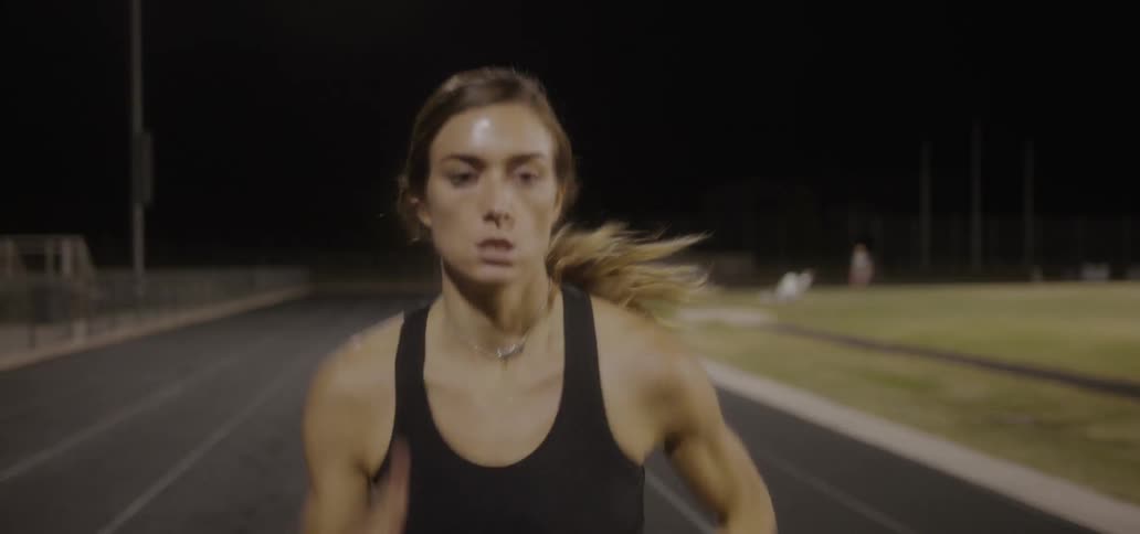A woman runs on the track at night