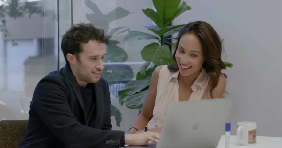 A man and woman sit at the laptop talking