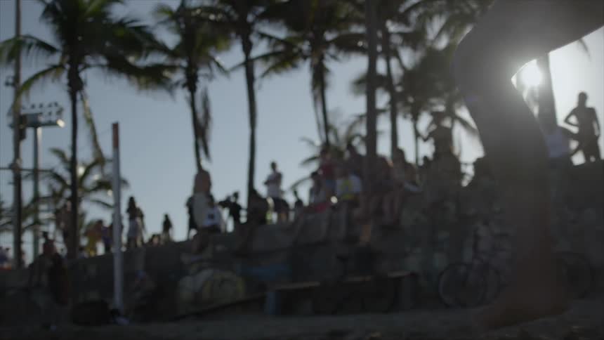 A person kicks the volleyball in the sand