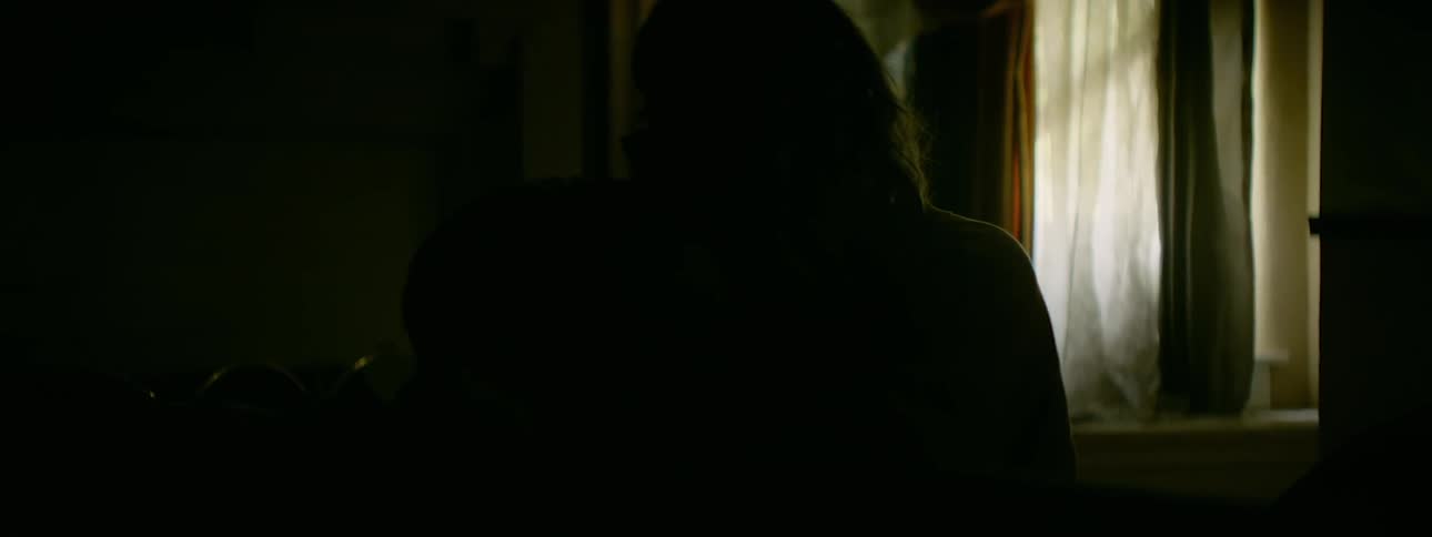 A man and woman kiss in the dark