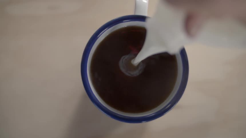Milk being poured into a cup of coffee