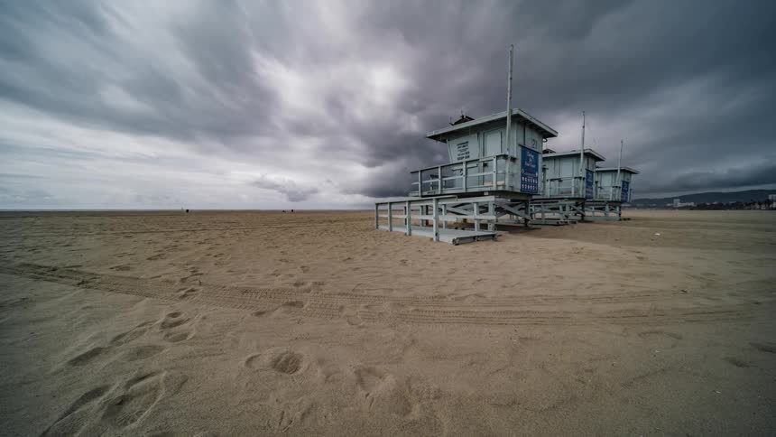 A lifeguard stand sits on the beach as people travel around it