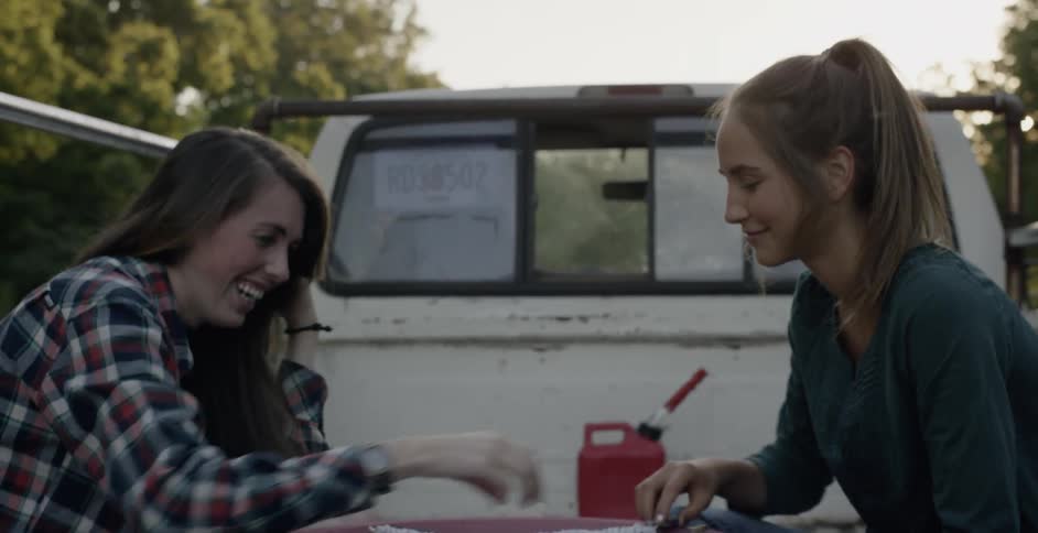 Two woman are playing checkers in the bed of truck
