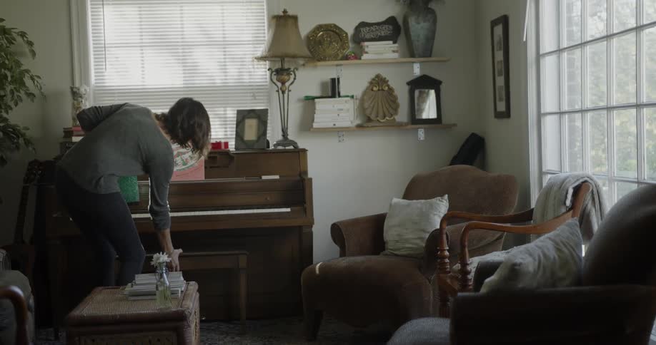 A woman walks over and sits at the piano