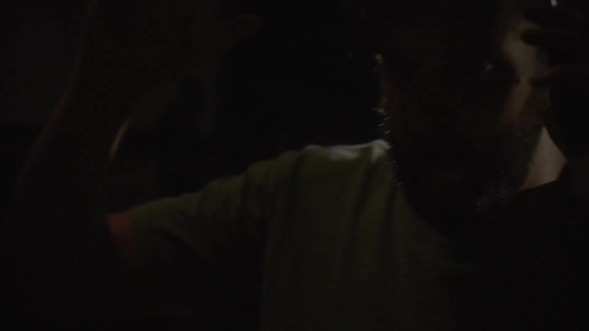 Man raises his arms as someone shines a flashlight on him