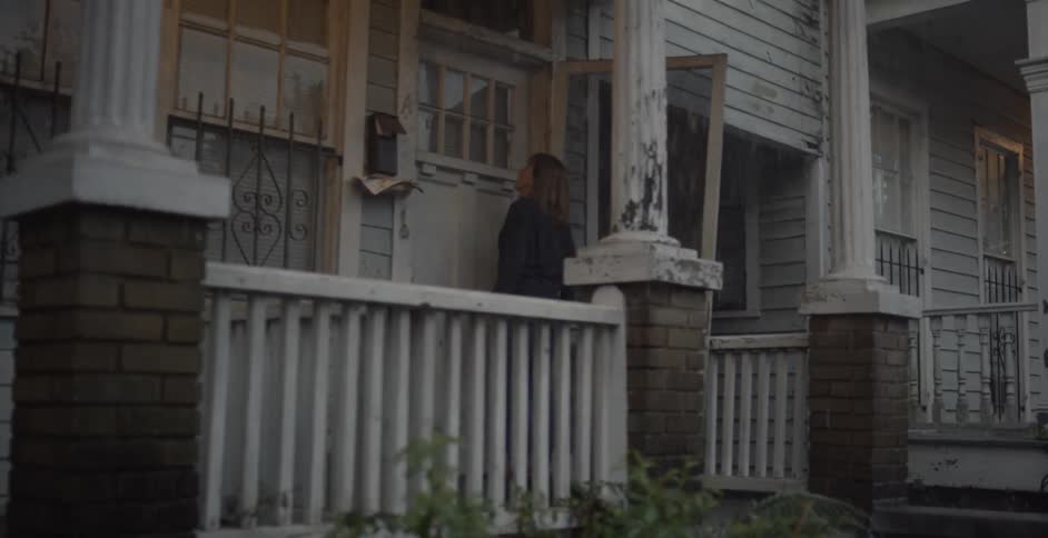 A woman stands on the porch and knocks on a door in the rain