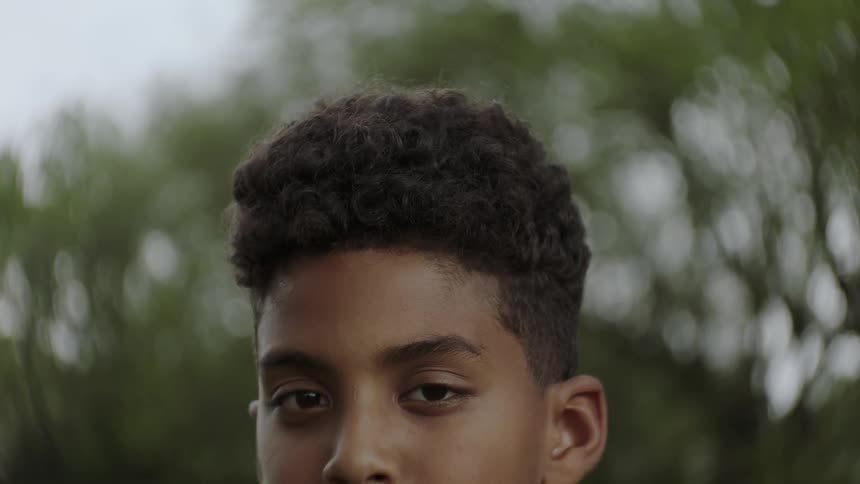 A young boy stands outside and stares forward