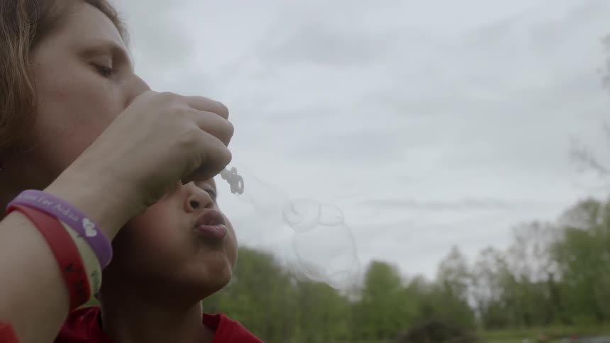 Woman and boy blow bubbles outside