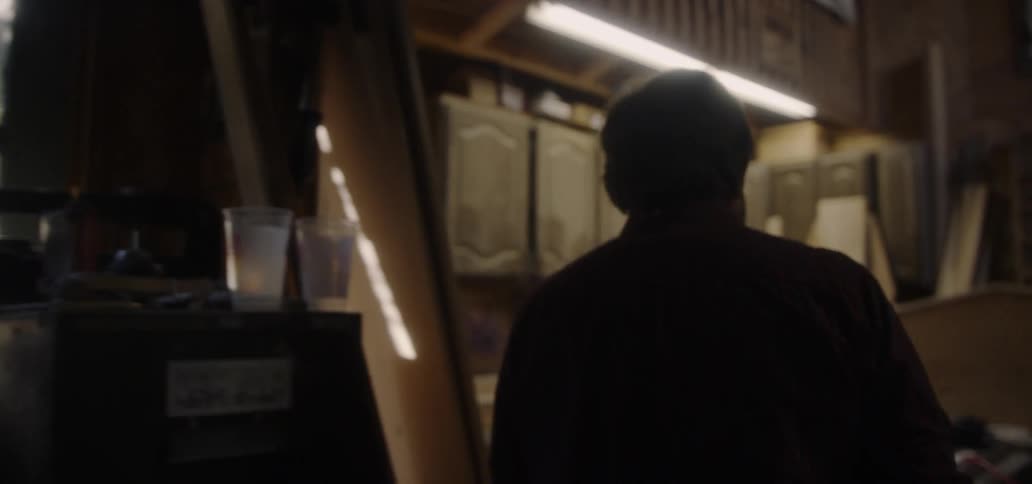 An old man is walking through a workshop in daylight