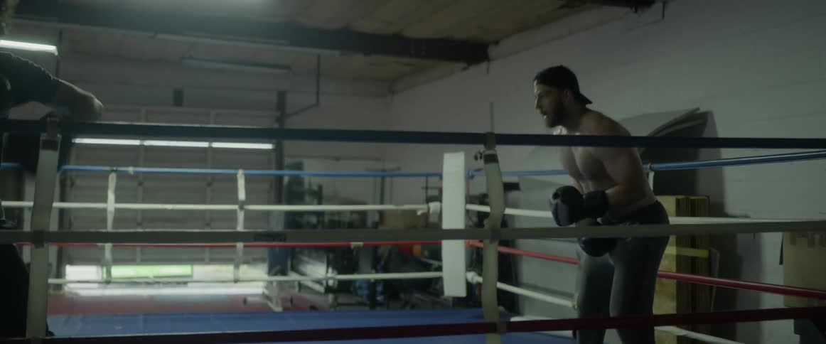 A boxer is sparring in the ring with a man using pads