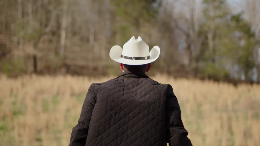 A man with a cowboy puts gloves on