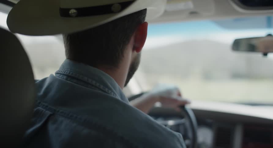 Man wearing a cowboy hat drives a vehicle