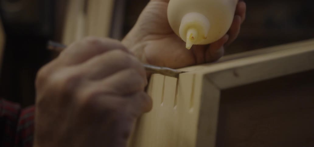 Man putting glue inside wood slits with brush