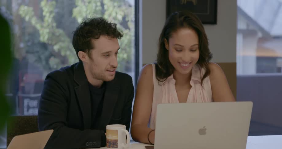 Coworkers talk while looking at a laptop