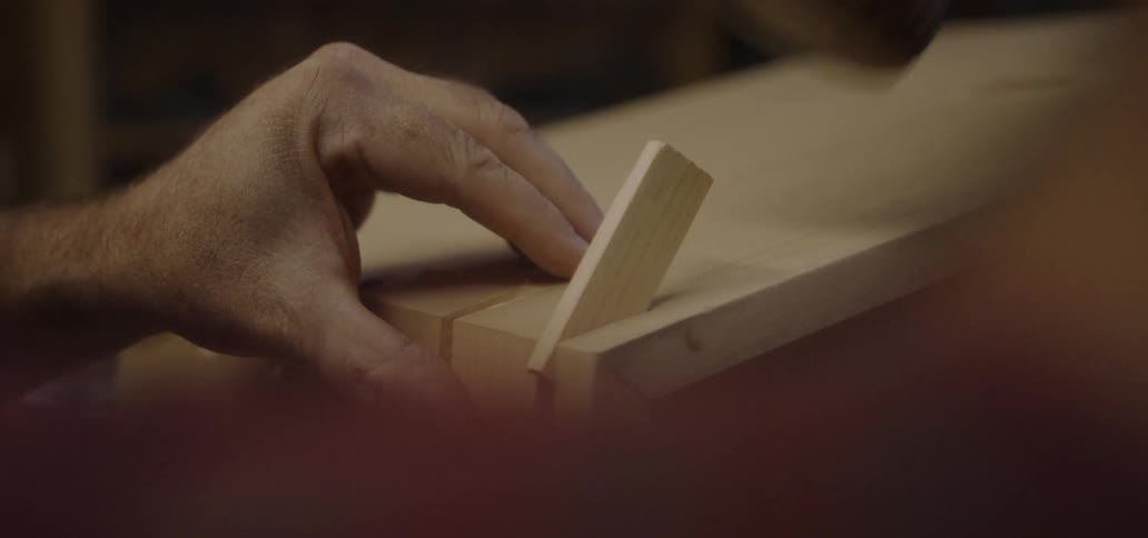 A person hammers wood into a notch