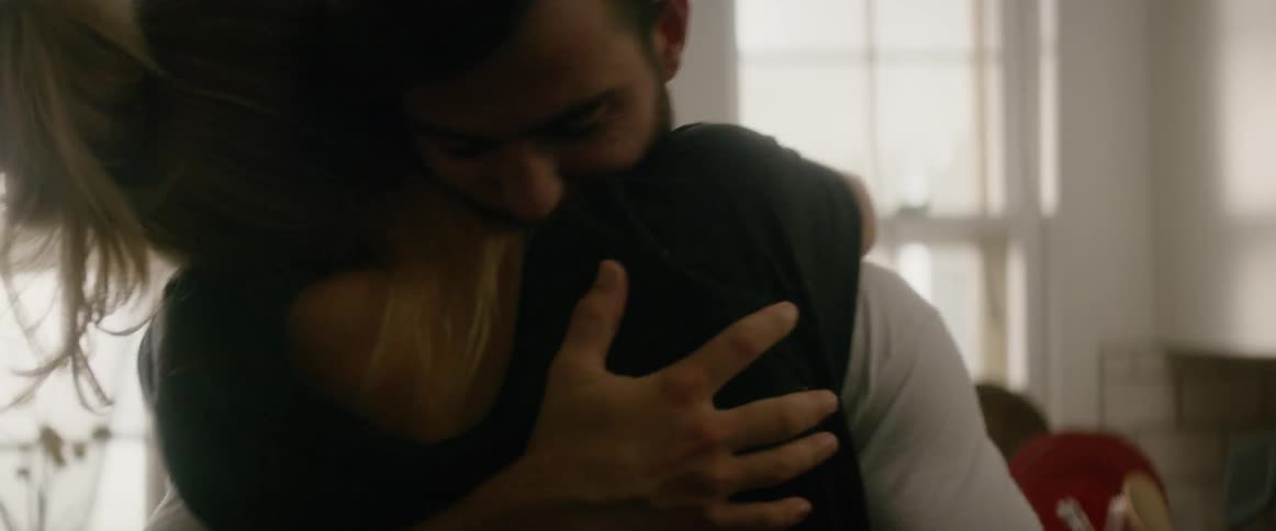 A couple are embracing and hugging inside their home during the day