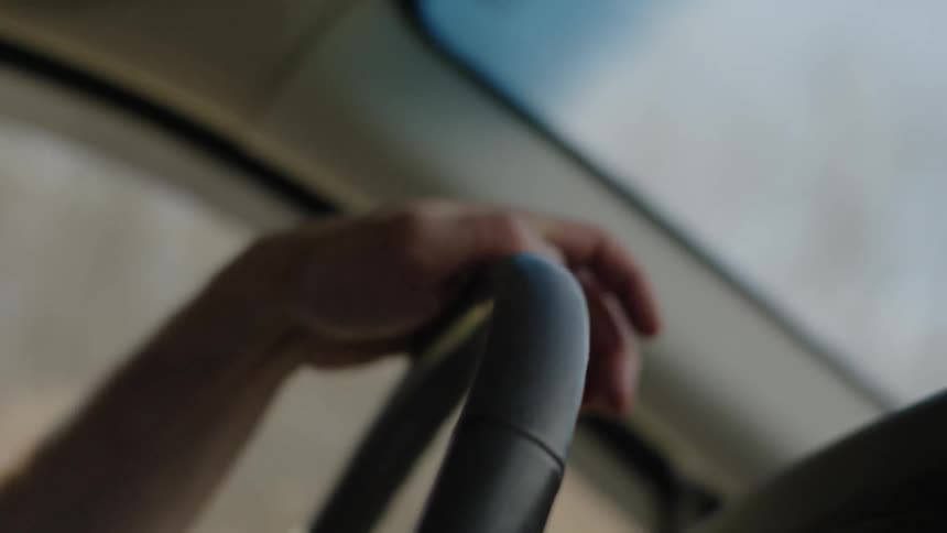 Man is steering and driving car during the day