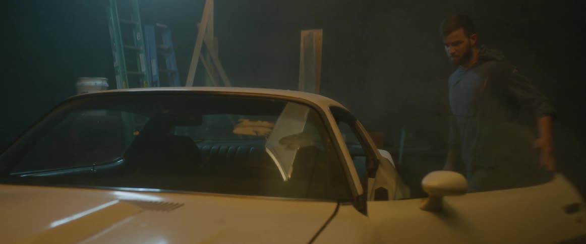 A man removes the car cover and gets in