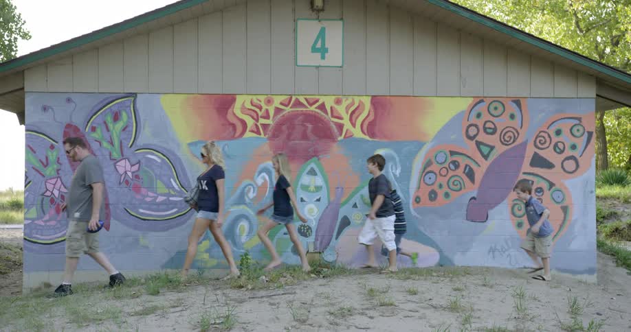 A man walks in front of a mural with friends
