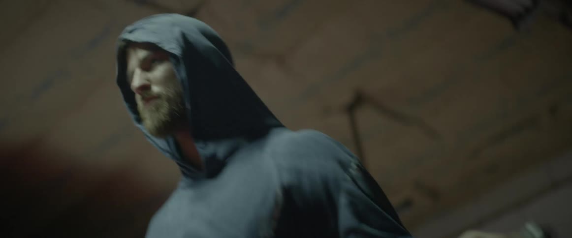 A man with his hood up jumps rope