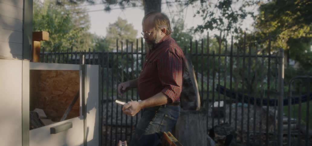 A man reaches into an outdoor wood bin