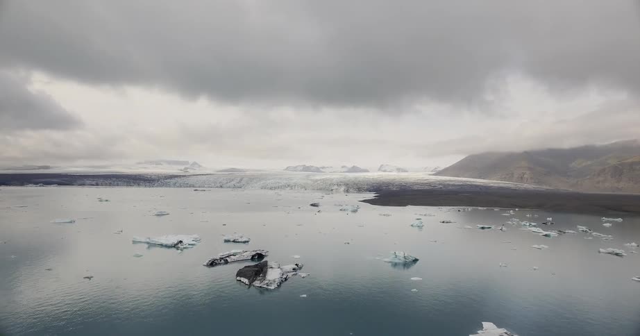 The water has ice floating around with thick clouds above