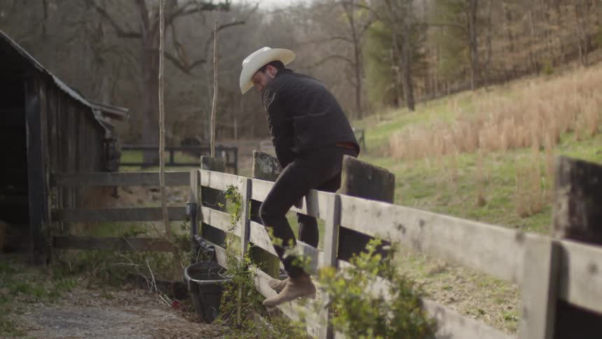 A man jumps over the fence of the farm