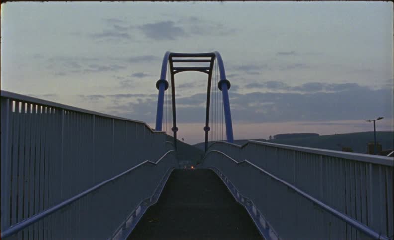 Dawn is breaking in the sky beyond a bridge