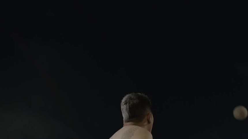 A man reaches up and hits the volleyball at night