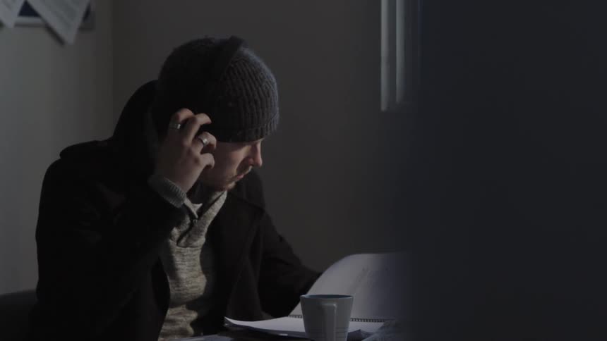 Man sits at a desk writing in a notebook