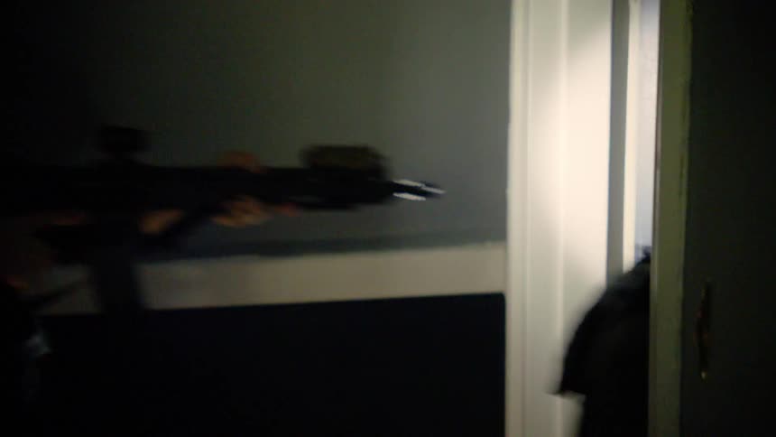 Men in tactical gear enter an apartment