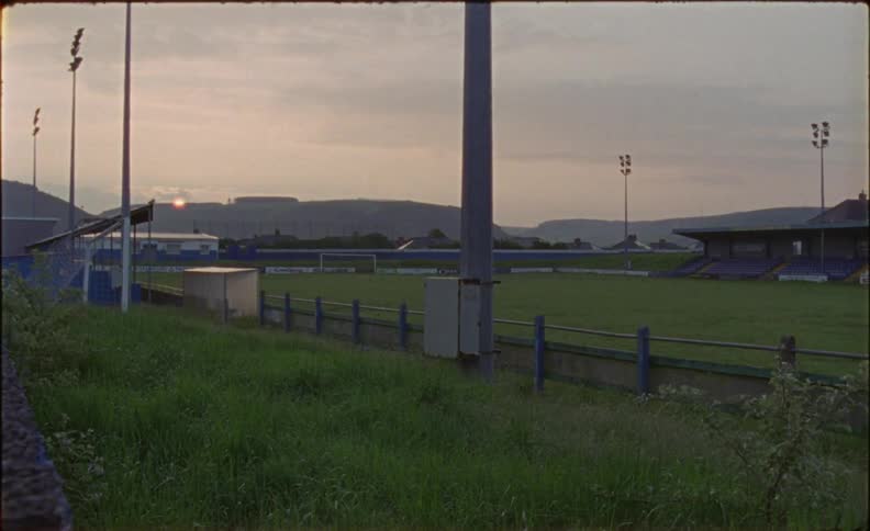 The sun sets behind a mountain behind an athletic field