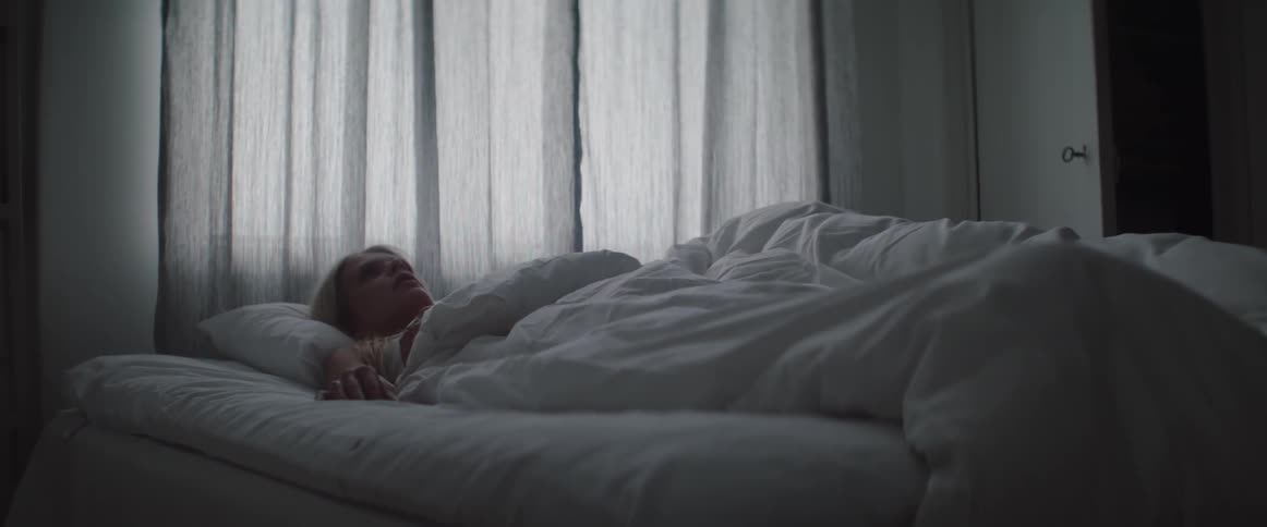 An anxious blonde woman lies awake in bed looking at ceiling.