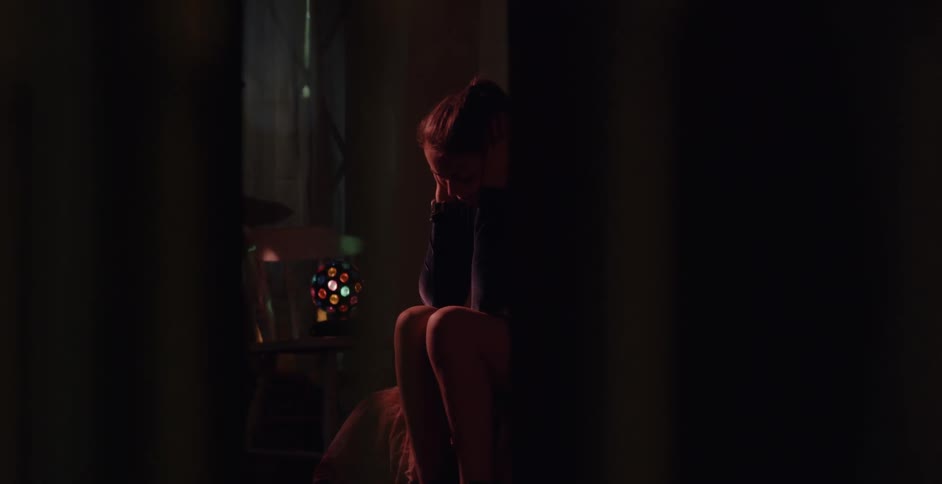 A girl is sitting on the edge of her bed thinking and crying at night
