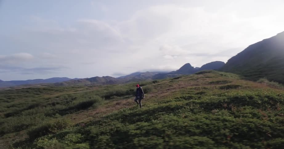 A hiker walks near mountains at sunset