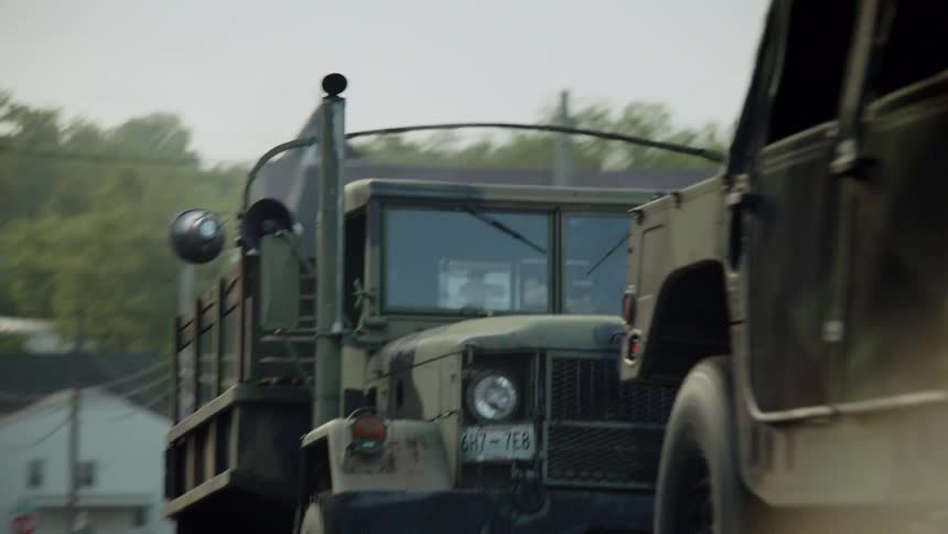 Military vehicles drive on a street