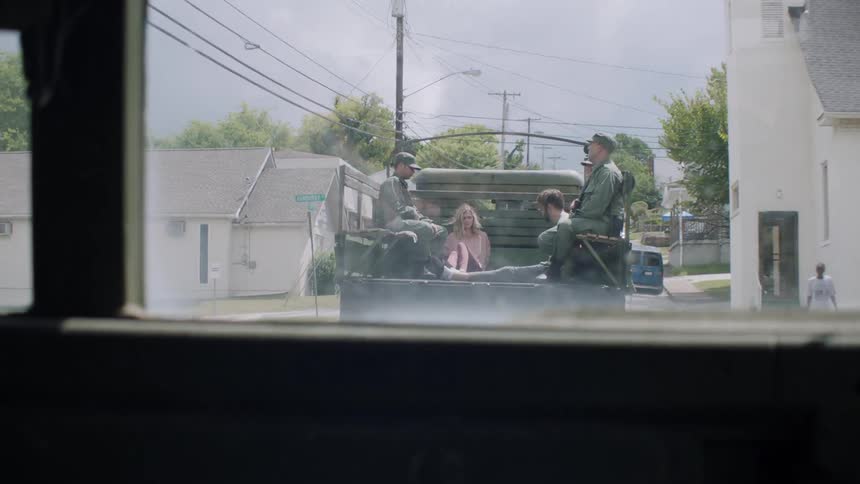 Soldiers ride in a truck bed with two prisoners