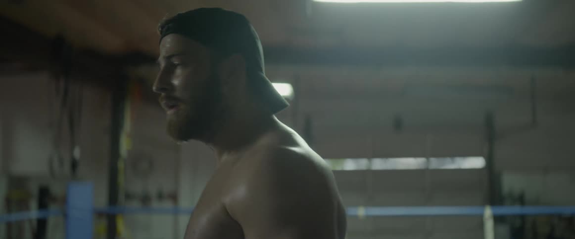 A shirtless man is breathing heavy in the ring as he walks around