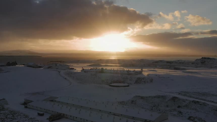 The sun is rising on the coastal horizon of a snow-covered community