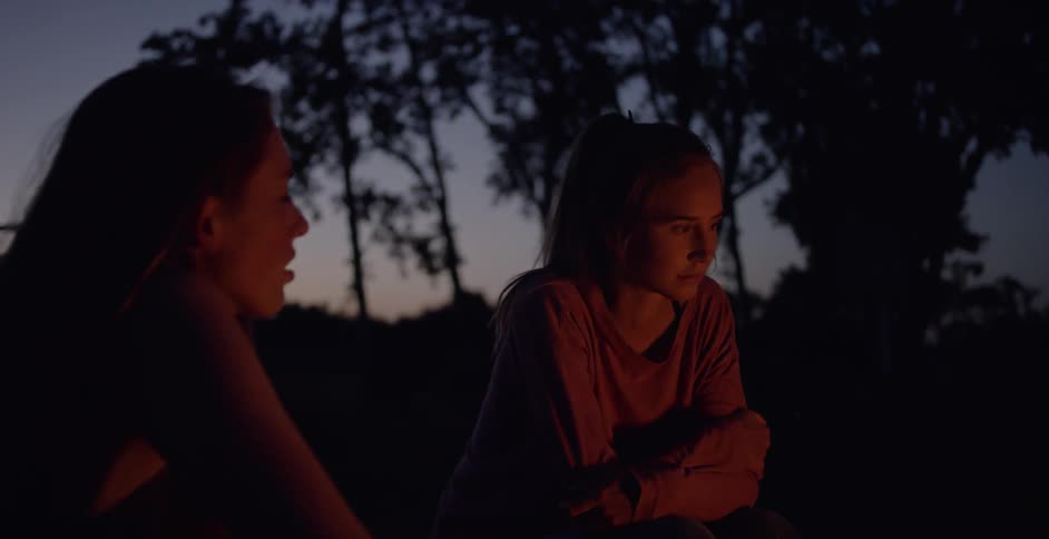 Women sit next to a campfire at dusk