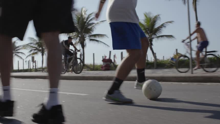 A young man dribbles a soccer ball on the asphalt