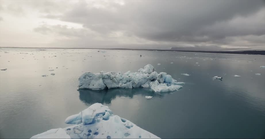 Icebergs are floating in the ocean on an overcast day