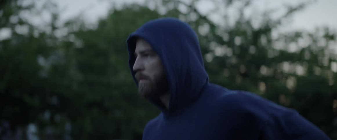 A man is running outside wearing a hooded shirt