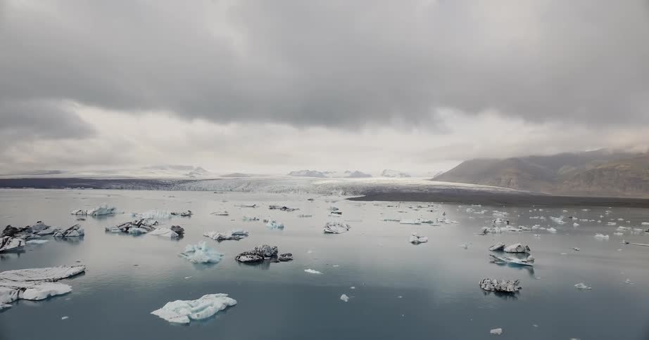 The shore has small icebergs floating nearby