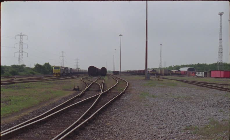 Train cars are sitting idle in a train yard in daylight