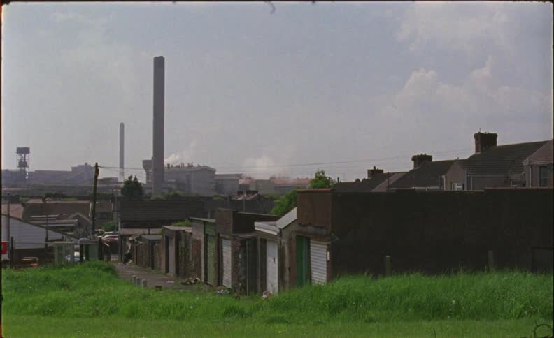 Smoke is rising from an industrial plant on the outskirts of a community during the day