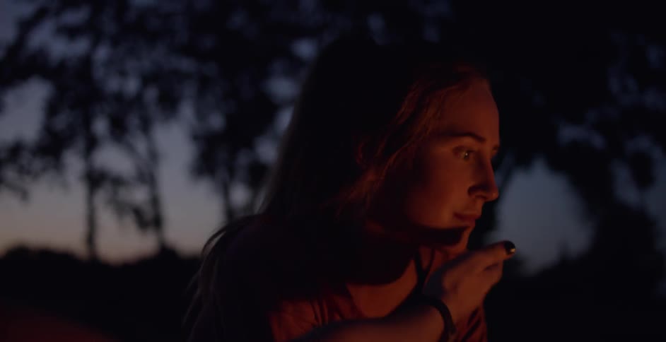 Two women talk while sitting by a campfire