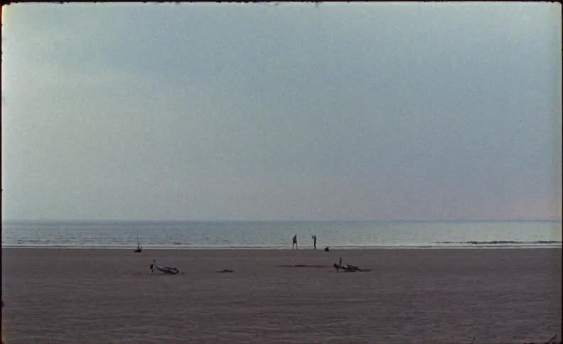 People walk along the nearly empty beach ahead