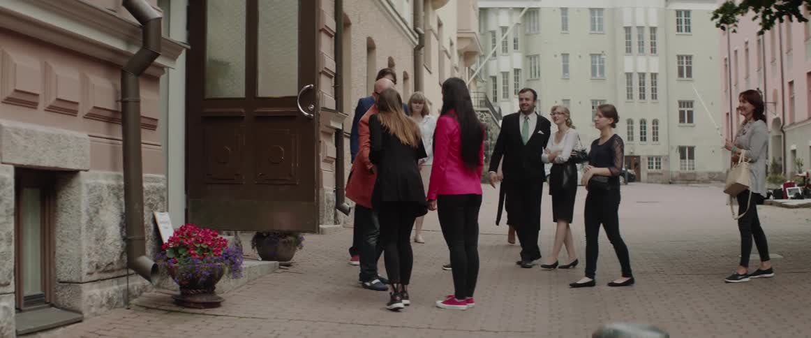 A group of people greet each other outside of a shop